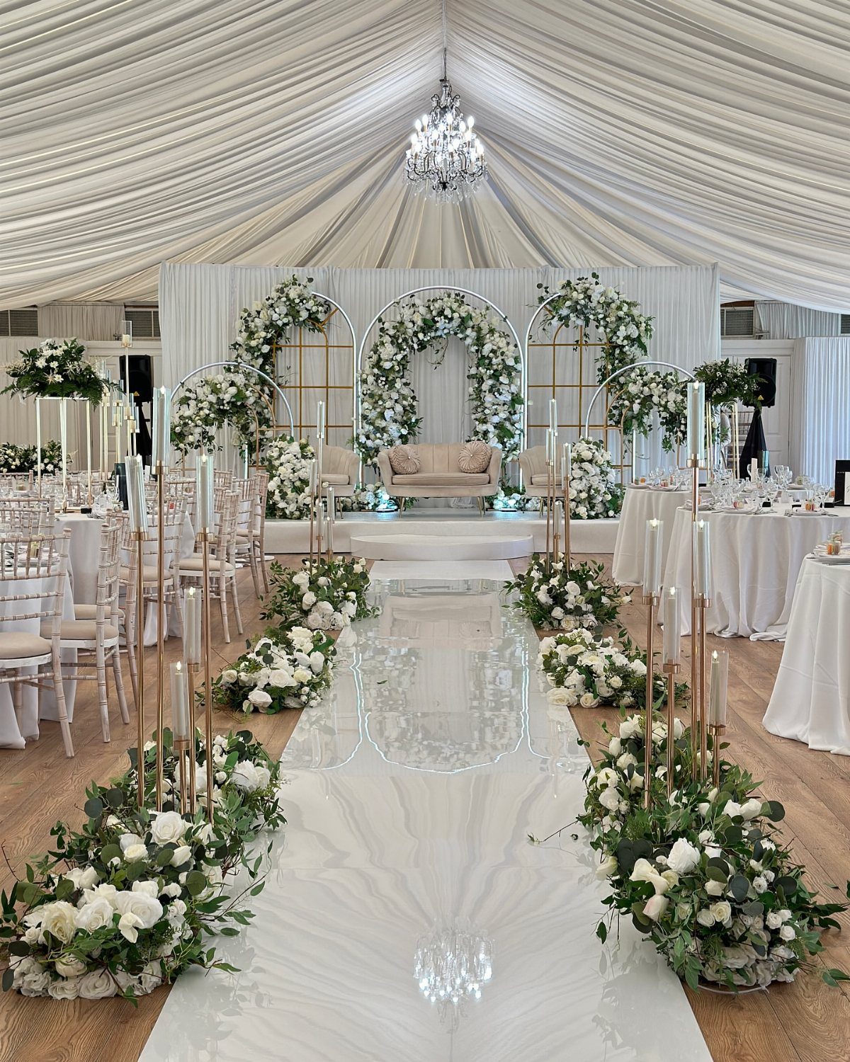 19 Wedding Backdrop Decorations for Any Ceremony Style 15 White floral wedding backdrop with gold arches and a white aisle runner.