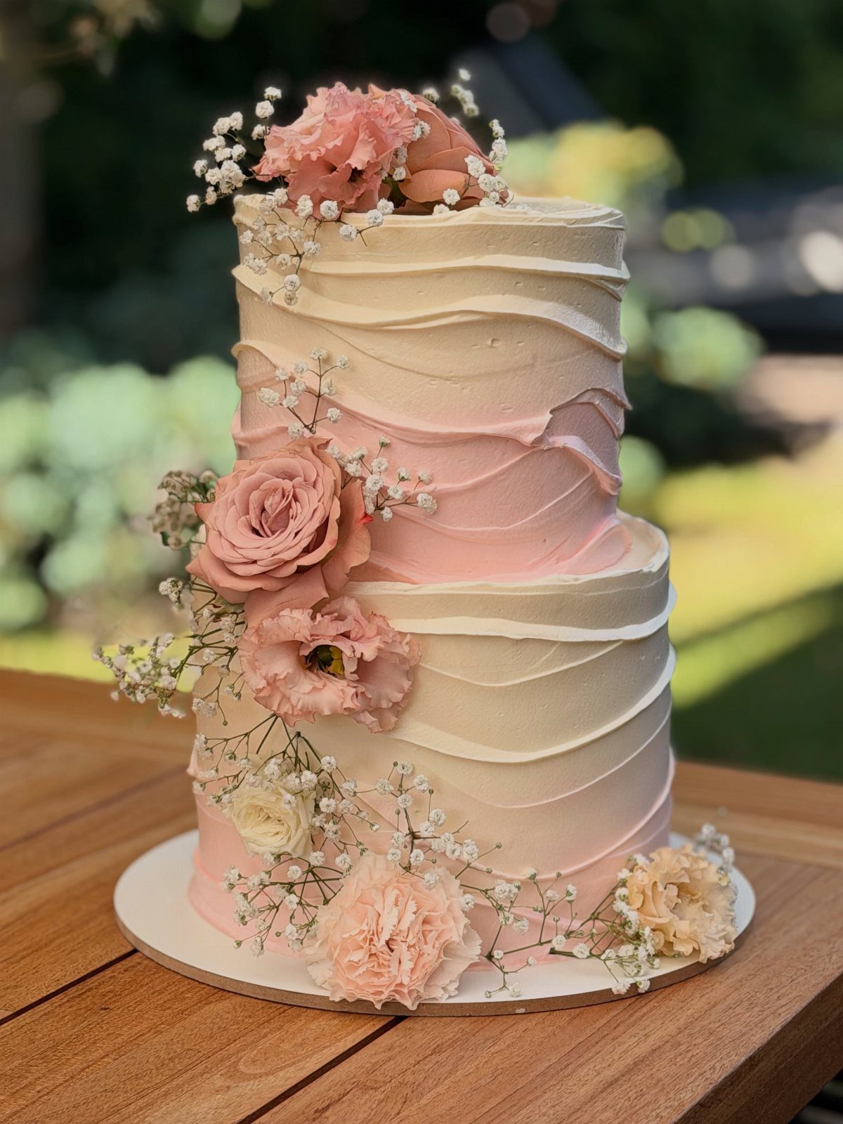 Wedding Cake Photo Ideas: 6 Designs for Every Style 1 Two-tier pink and white buttercream cake decorated with fresh roses and baby's breath.