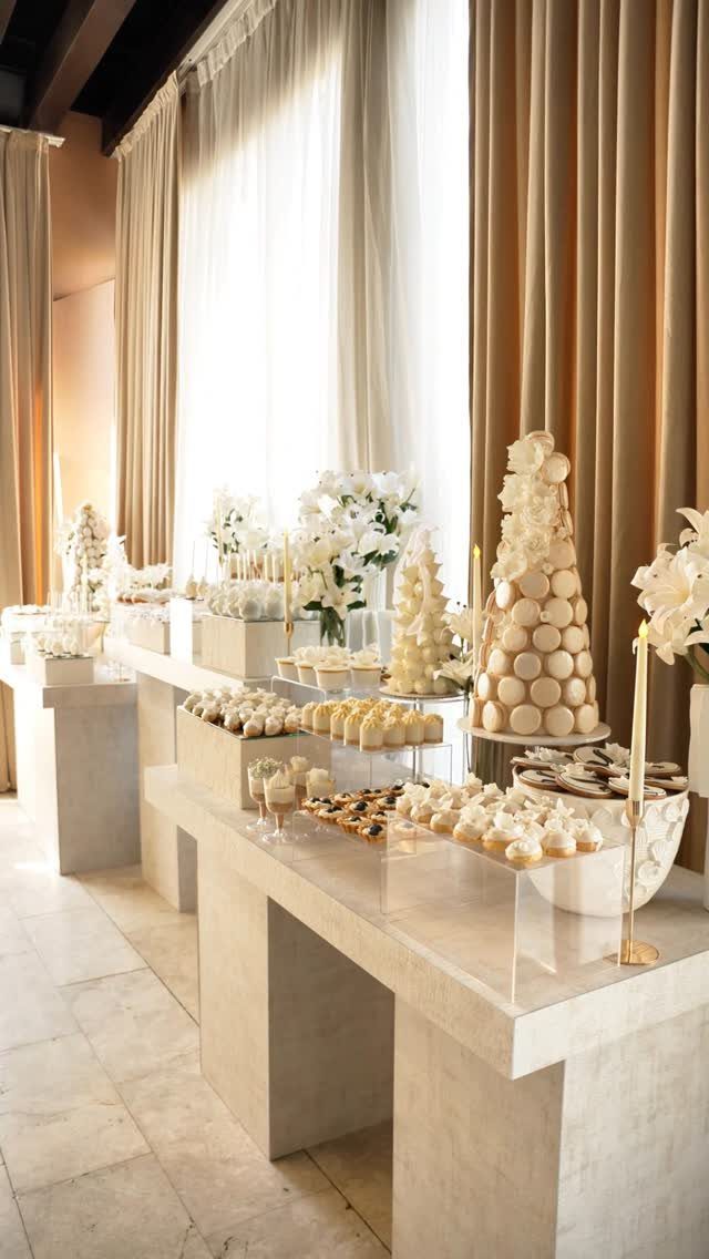 5 Wedding Cake Pops Ideas for Favors and Dessert Tables 4 Elegant white dessert table featuring cake pop towers and macarons in a bright room.