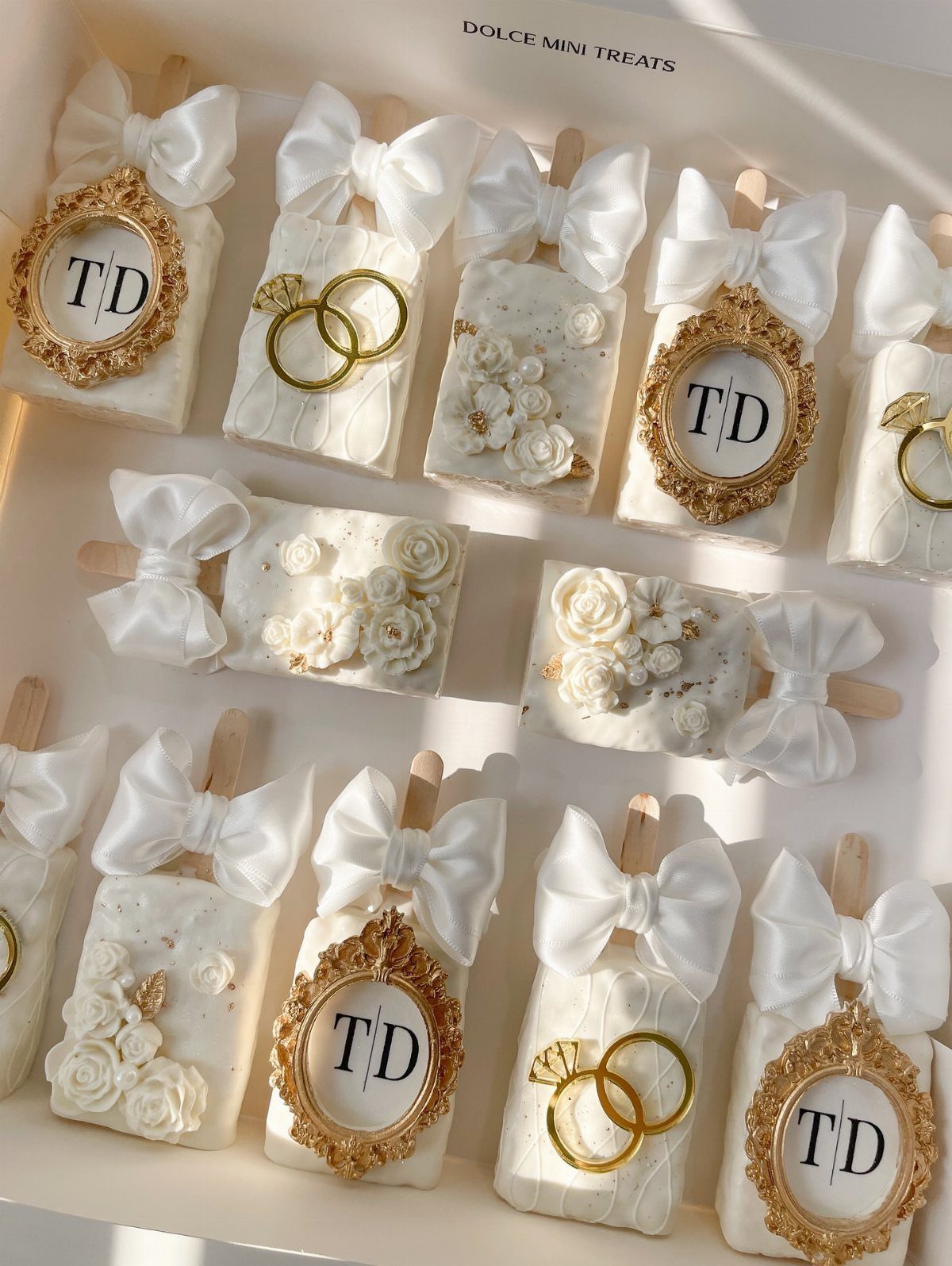 5 Wedding Cake Pops Ideas for Favors and Dessert Tables 5 White wedding cake pops with gold rings, monograms, and white satin bows.