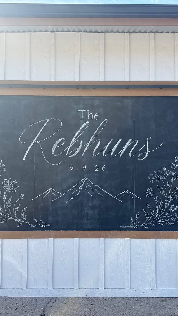 19 Wedding Decorations at Home: DIY Ideas to Try 4 Chalkboard welcome sign with white calligraphy, mountain drawings, and floral accents on white wall.