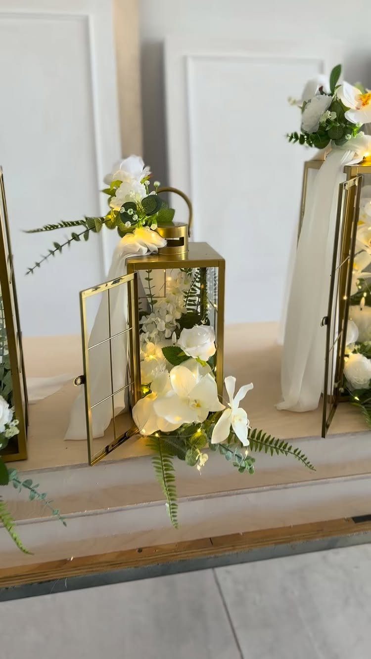 19 Wedding Decorations at Home: DIY Ideas to Try 9 Gold glass lanterns with white flowers and fairy lights on a wooden surface