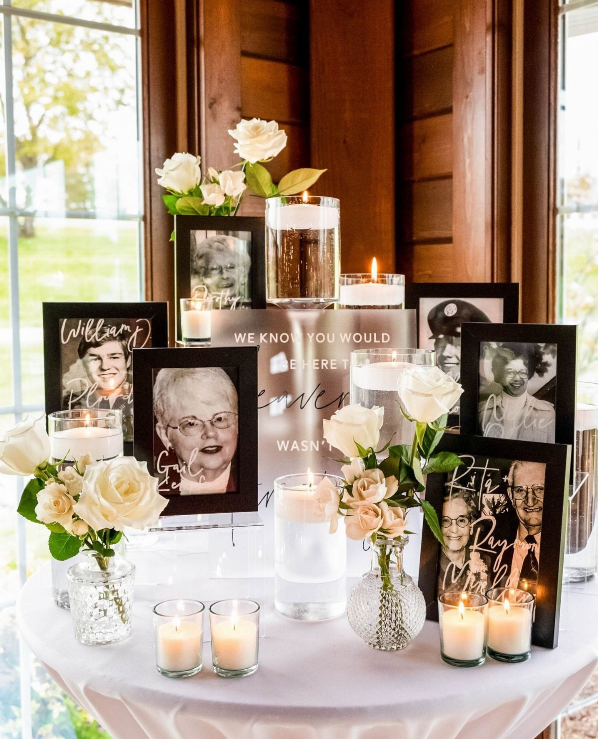 19 Wedding Decorations at Home: DIY Ideas to Try 10 Memory table with framed portraits, white roses, and glowing candles on a white cloth.