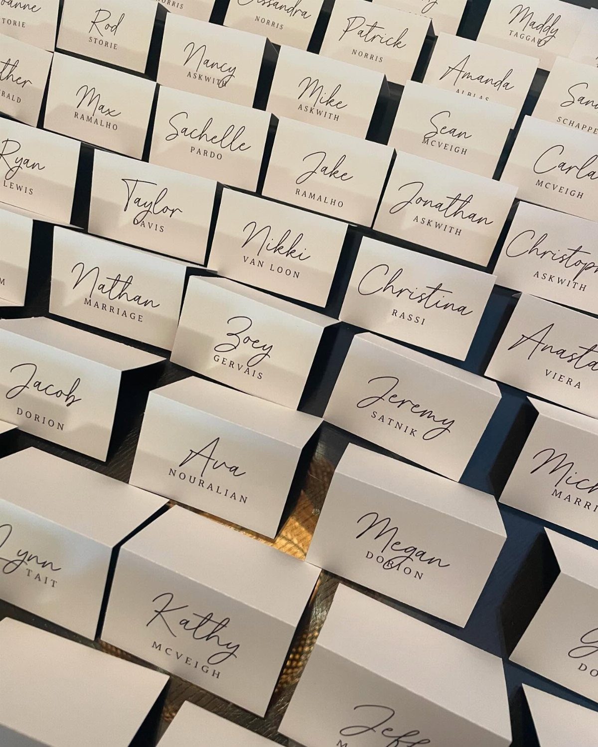 19 Wedding Decorations at Home: DIY Ideas to Try 8 White folded place cards with blue cursive names arranged in neat rows.