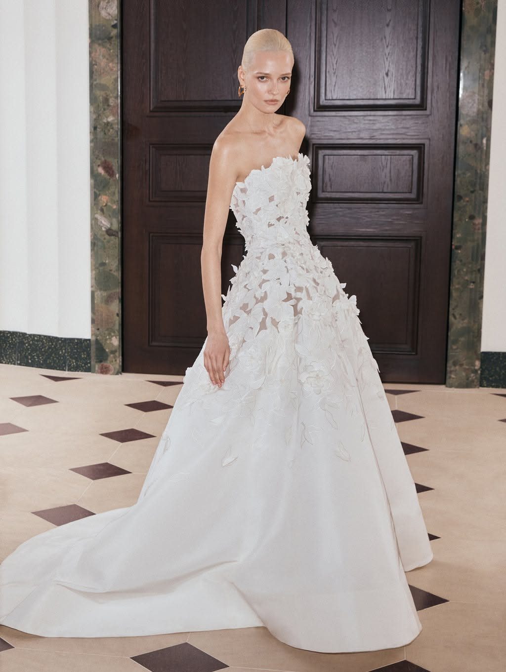 Woman in a high-end strapless white wedding dress with floral details and full skirt.