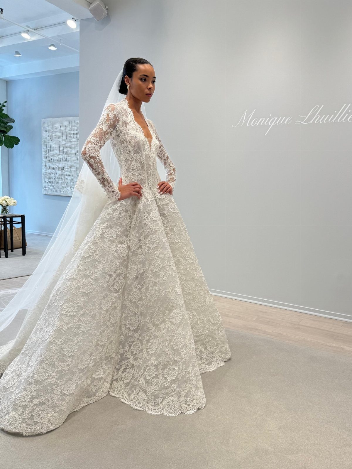Woman in a white lace Monique Lhuillier wedding dress with a long veil.