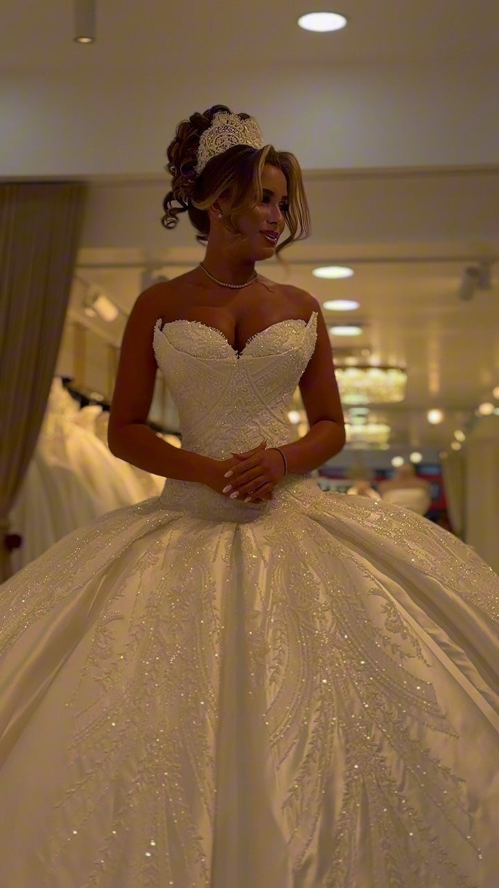 Woman in a white strapless ball gown with a voluminous sparkling skirt and tiara.