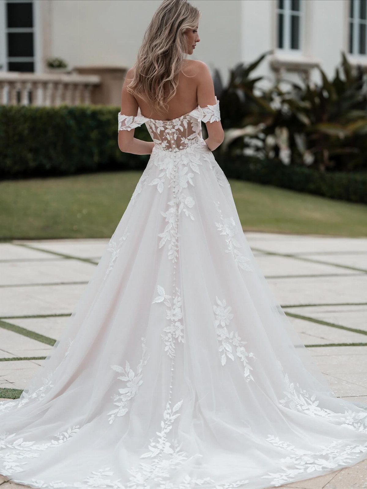 Wedding Dress Options: 8 Silhouettes From A-Line to Vintage 1 Woman wearing a white A-line wedding dress with lace floral embroidery and long train.