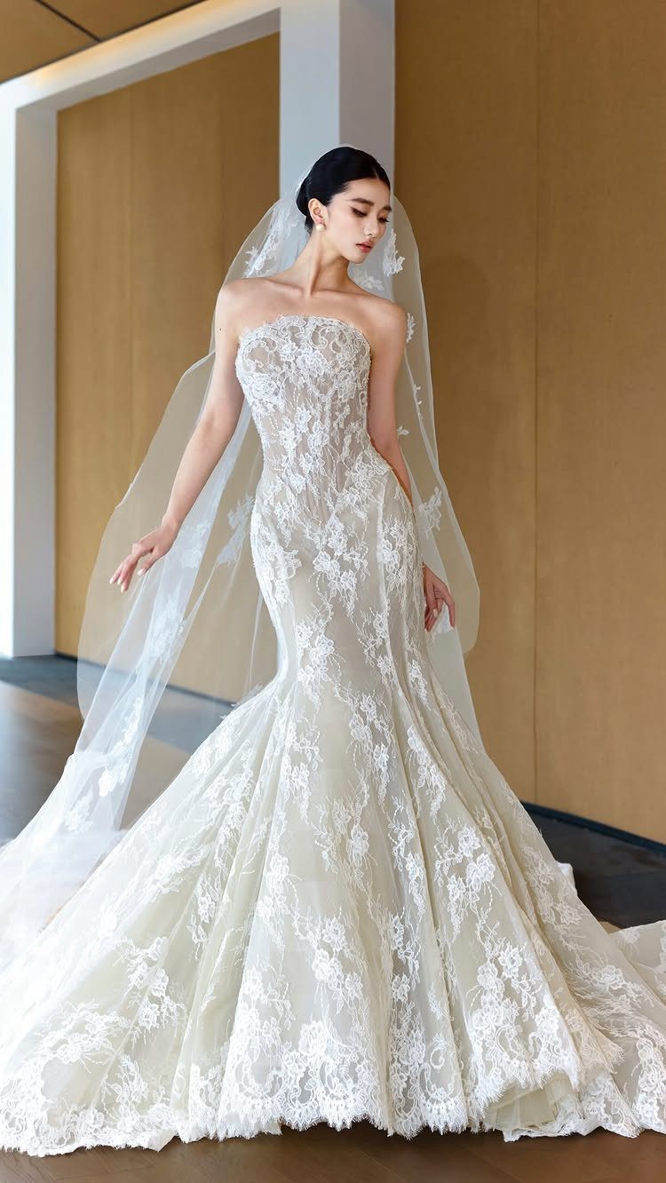 Wedding Dress Options: 8 Silhouettes From A-Line to Vintage 3 Woman in a strapless white lace mermaid wedding dress with a long veil.