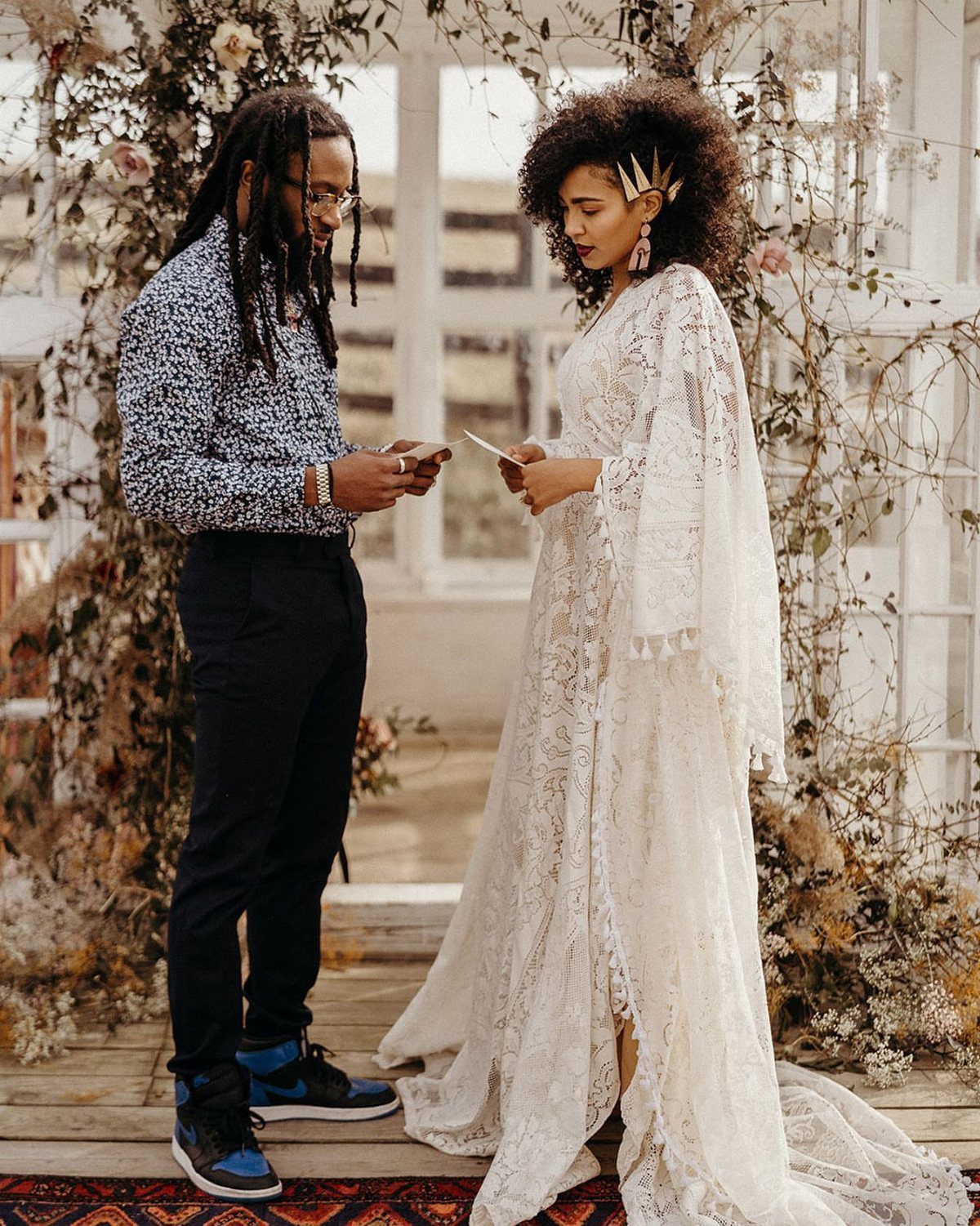 Woman in a white lace boho wedding dress standing with a man in a gazebo.