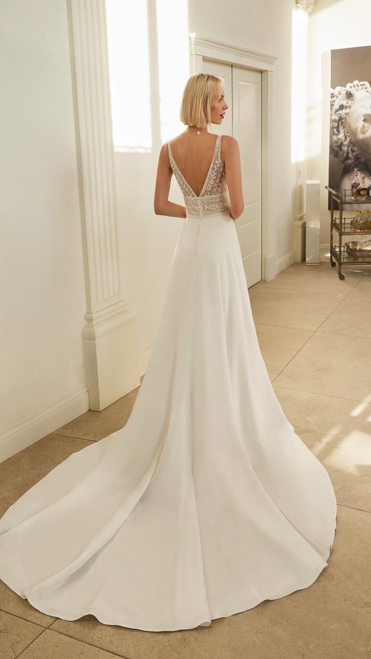 Woman in a white A-line wedding dress with a lace V-back bodice.