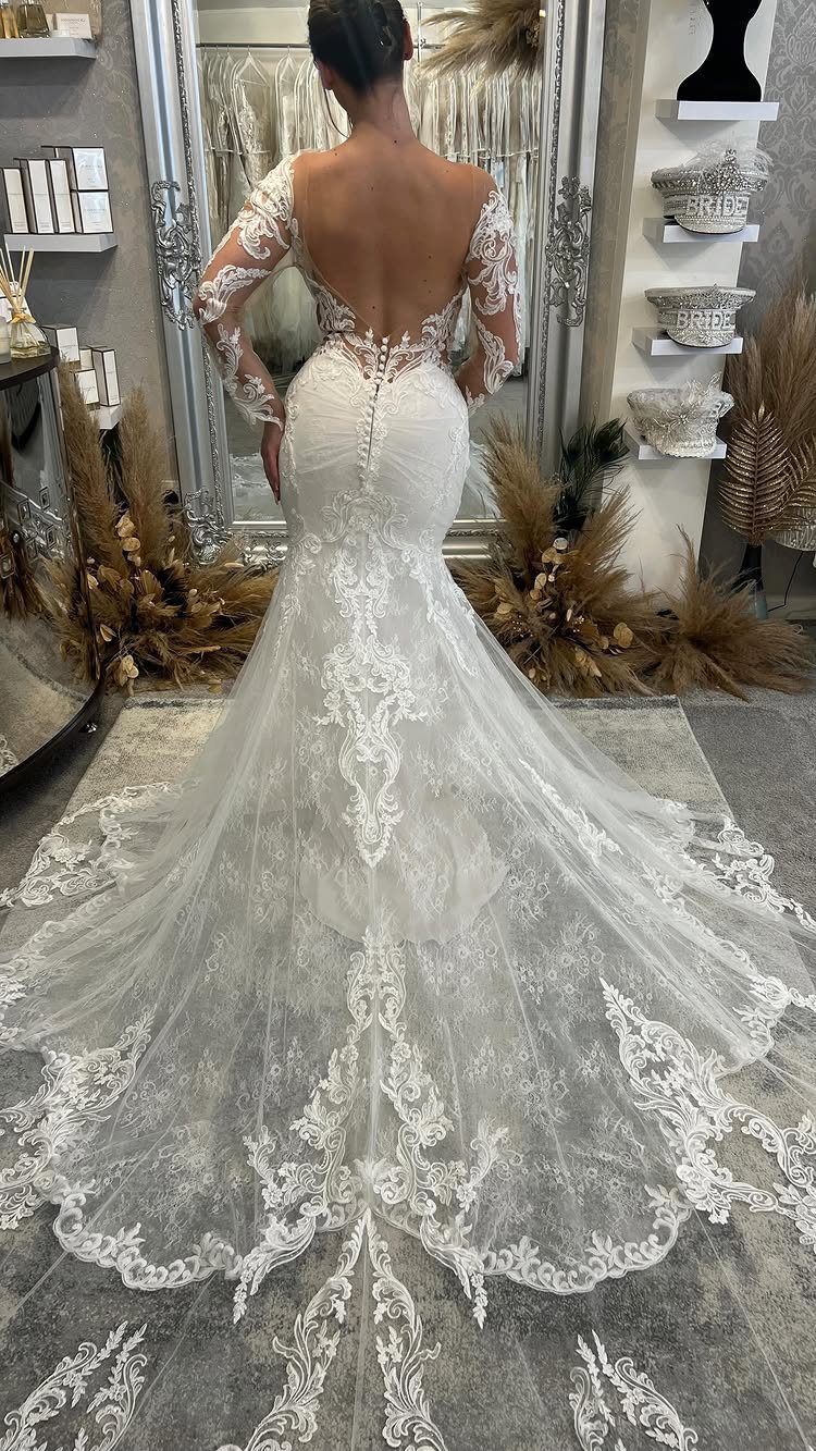 Woman wearing a white lace mermaid wedding dress with a long ornate train.