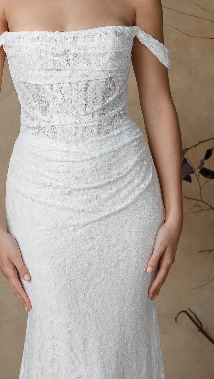 White lace wedding dress with off-the-shoulder straps and a fitted silhouette.