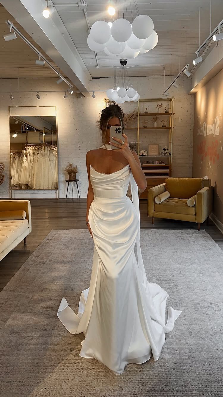 Wedding Dresses Elegant and Classy: 14 Gown Styles 2 Woman in a white satin wedding dress with an asymmetric neckline and long train.