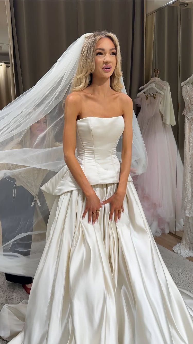 Wedding Dresses Elegant and Classy: 14 Gown Styles 3 Woman in a strapless white satin wedding gown and long veil in a bridal salon