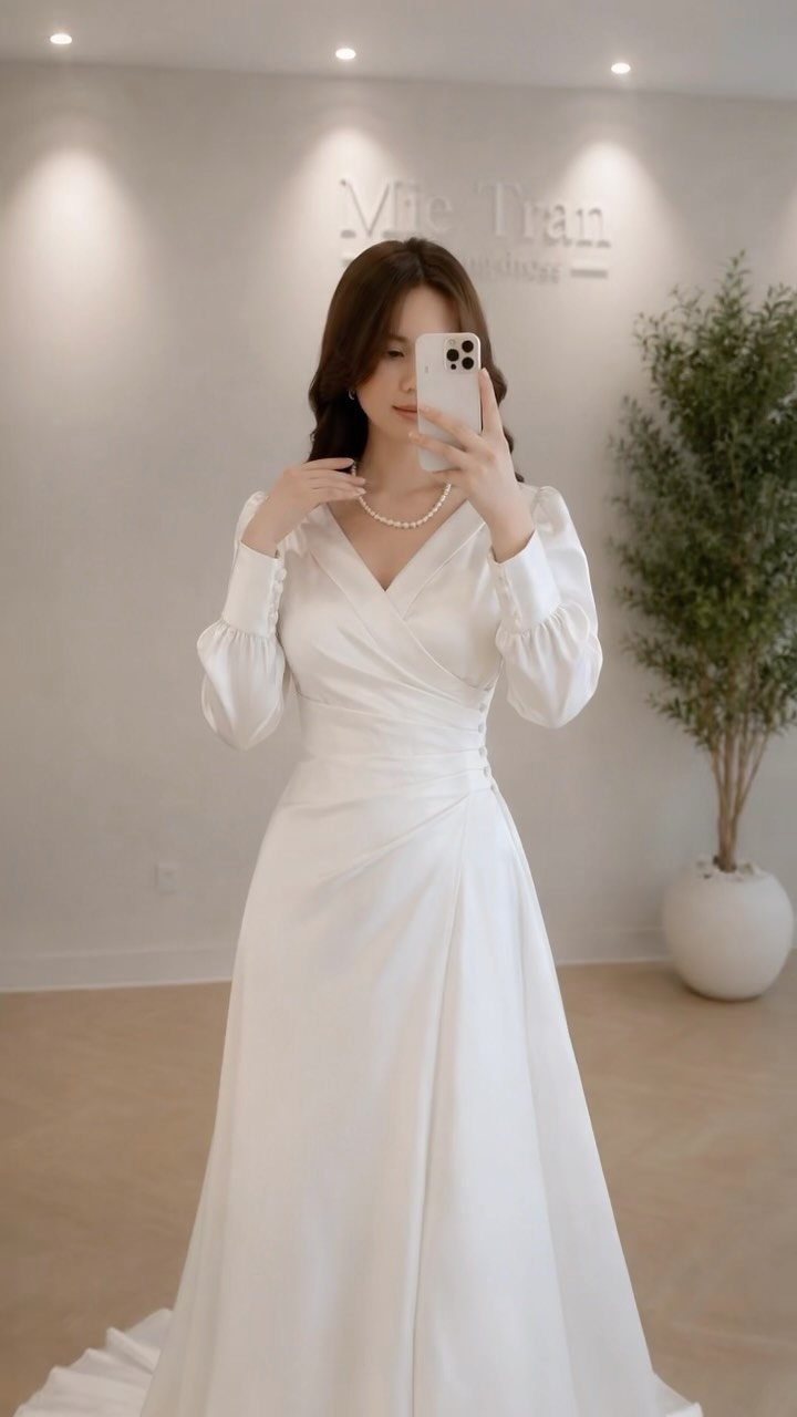 Wedding Dresses Elegant and Classy: 14 Gown Styles 5 Woman in a white satin V-neck wedding dress with long sleeves and pearl necklace.