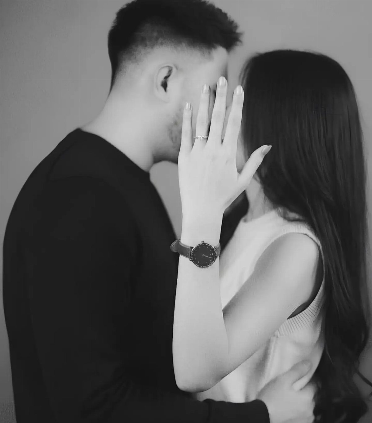Couple embracing in a black and white minimalist setting with a plain background.