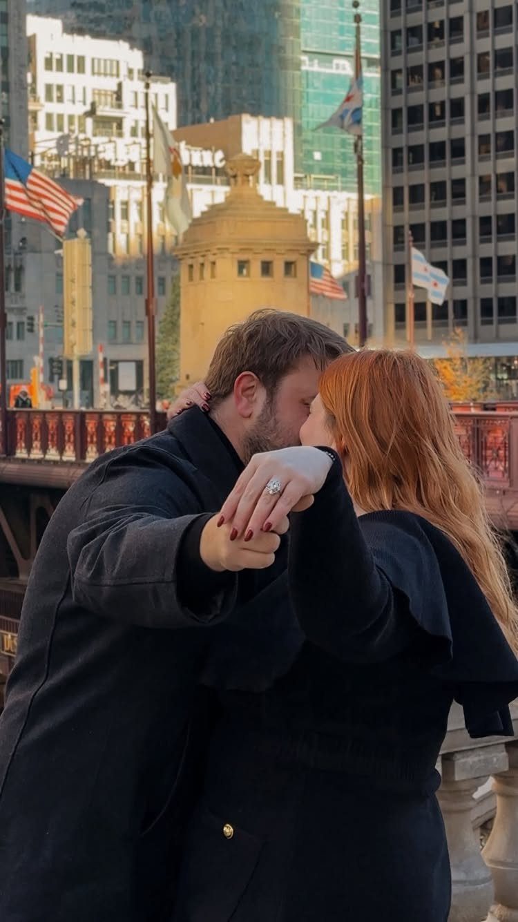 Couple kissing in a city, with a close-up view of an engagement ring.