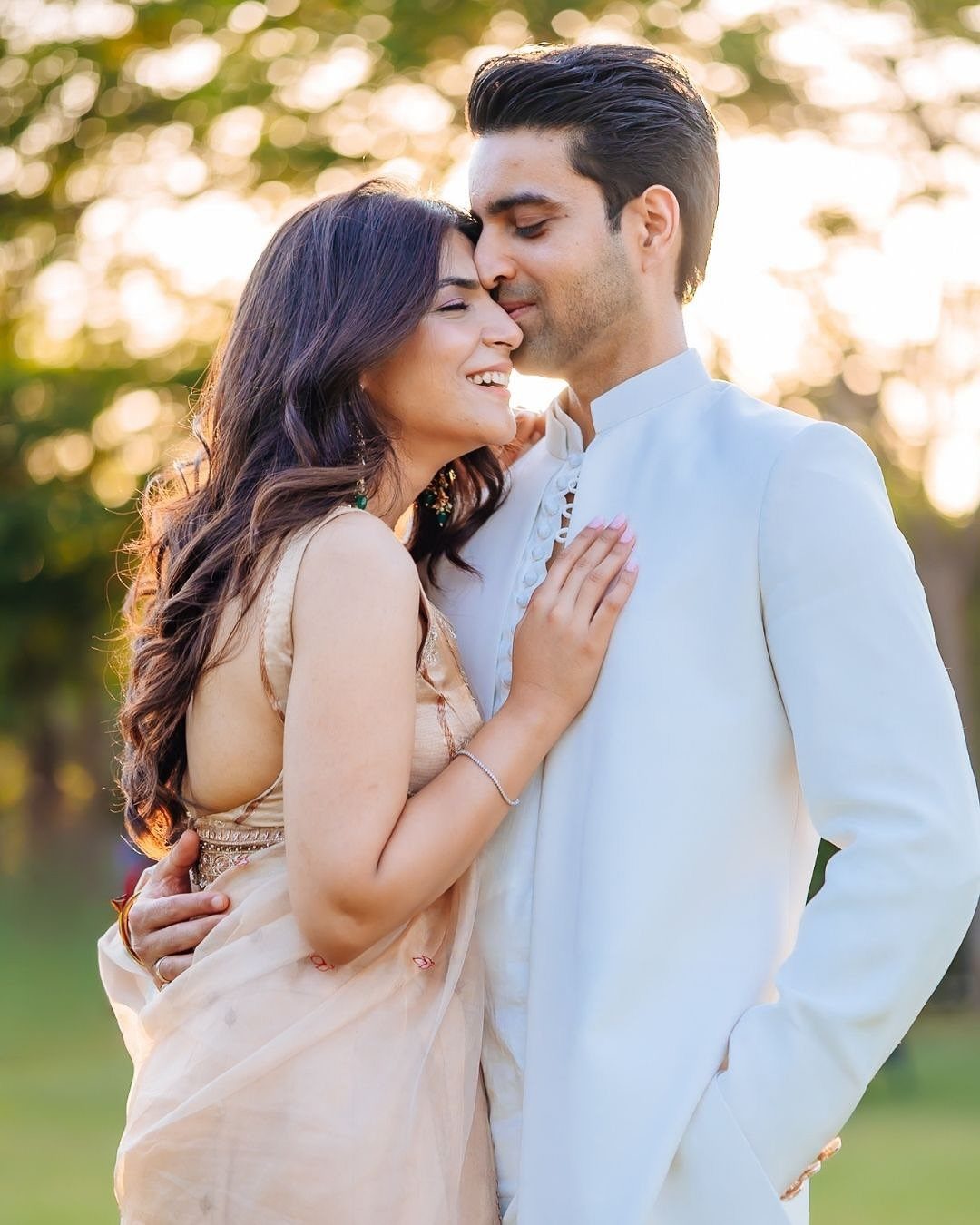 Couple in traditional Indian clothing embracing and smiling during an outdoor engagement shoot.