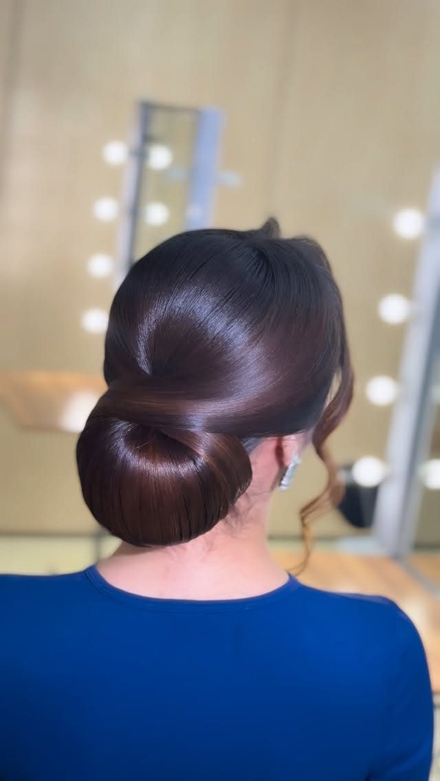 Polished low bun hairstyle on dark brown hair with a royal blue top.