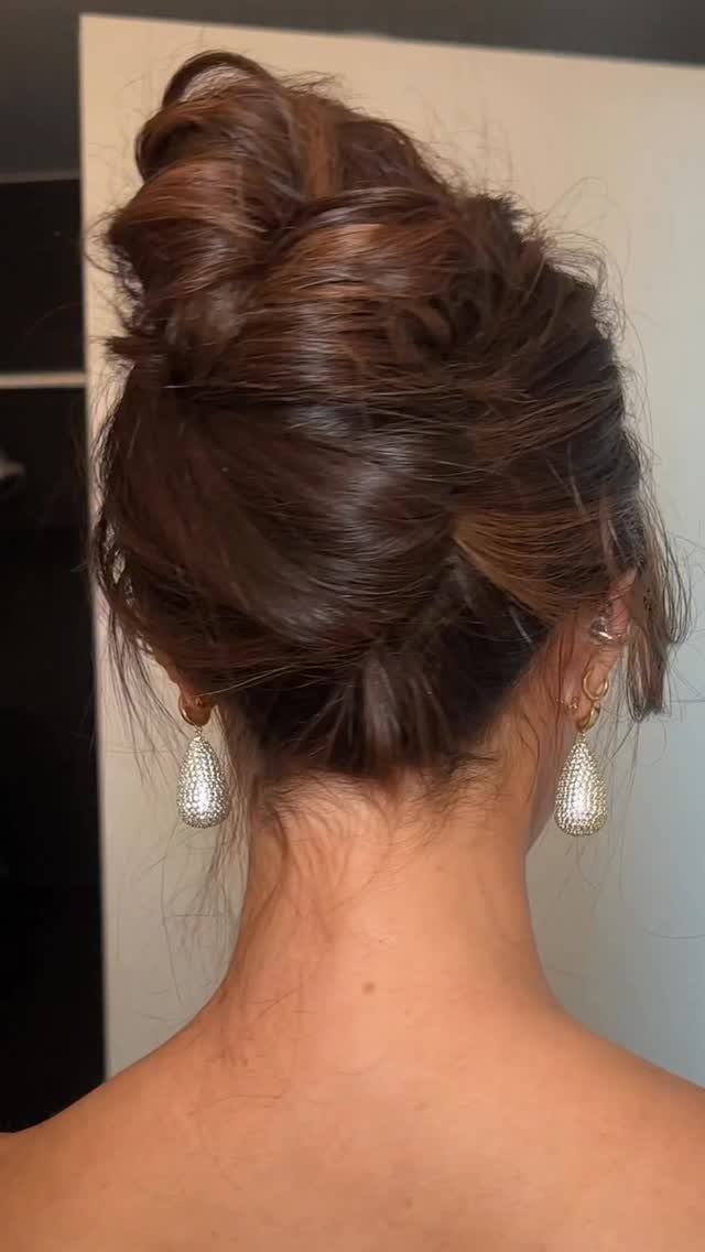 Brown hair styled in a voluminous textured updo with sparkling teardrop earrings.