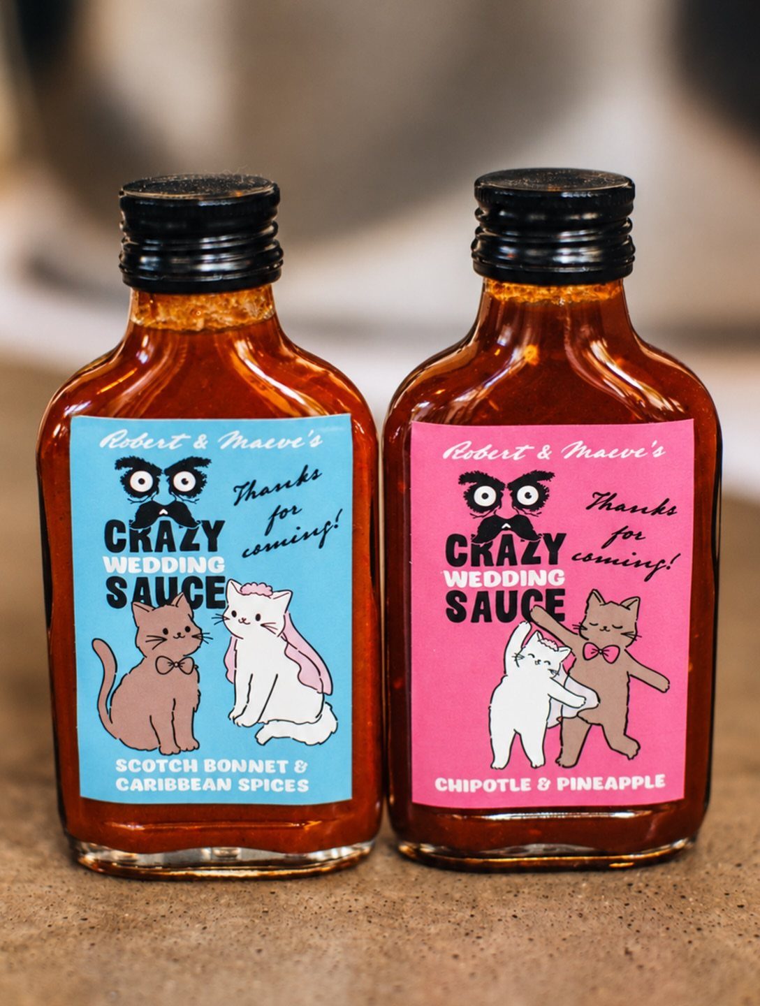 30 Wedding Guest Keepsakes Your Guests Will Actually Use 23 Two small bottles of hot sauce with personalized wedding labels and cartoon cats.