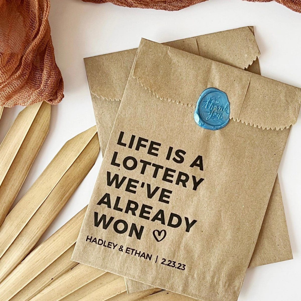 30 Wedding Guest Keepsakes Your Guests Will Actually Use 28 Brown kraft envelopes with lottery themed wedding text and a blue wax seal.