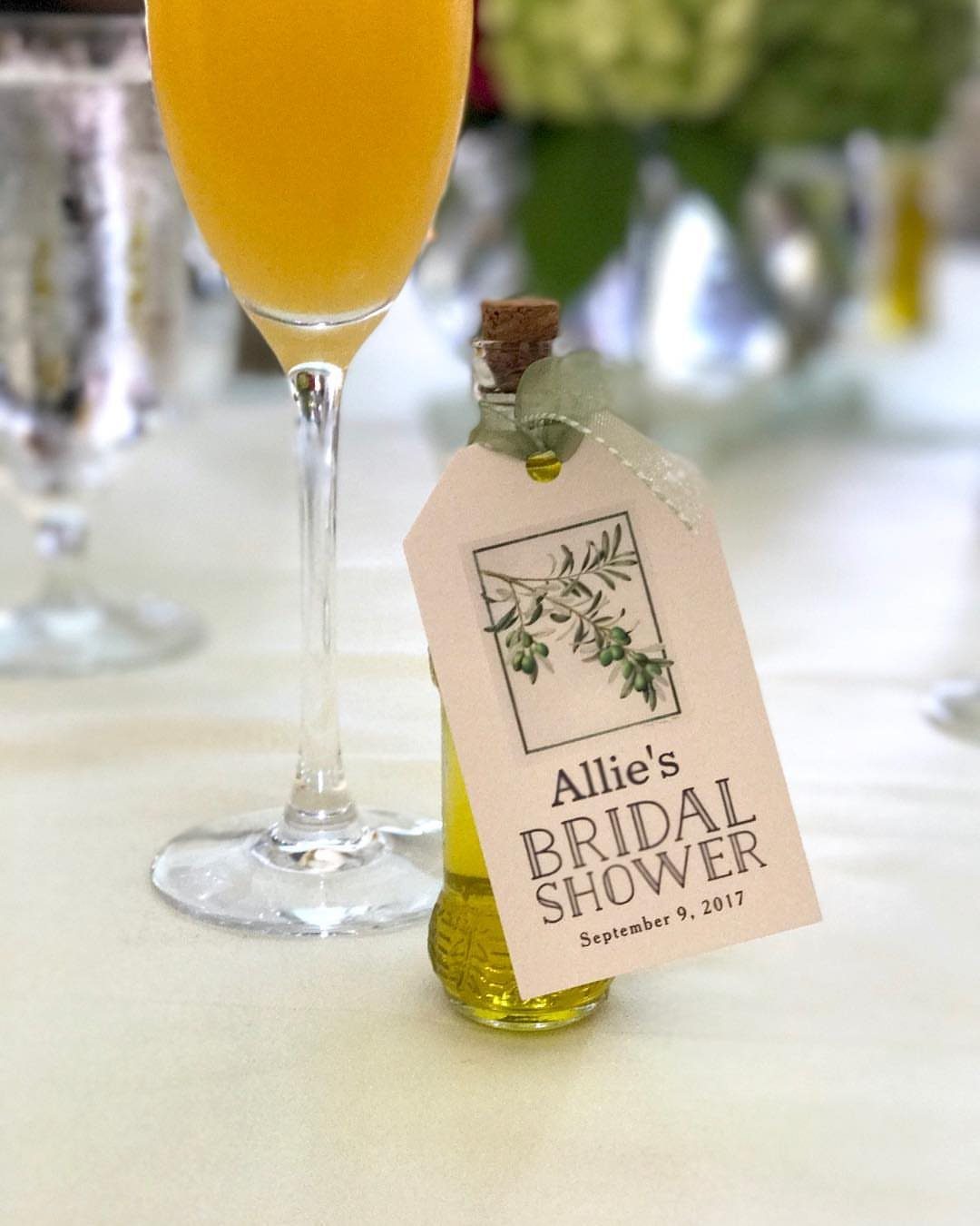30 Wedding Guest Keepsakes Your Guests Will Actually Use 19 Mini olive oil bottle with a bridal shower gift tag and green ribbon.
