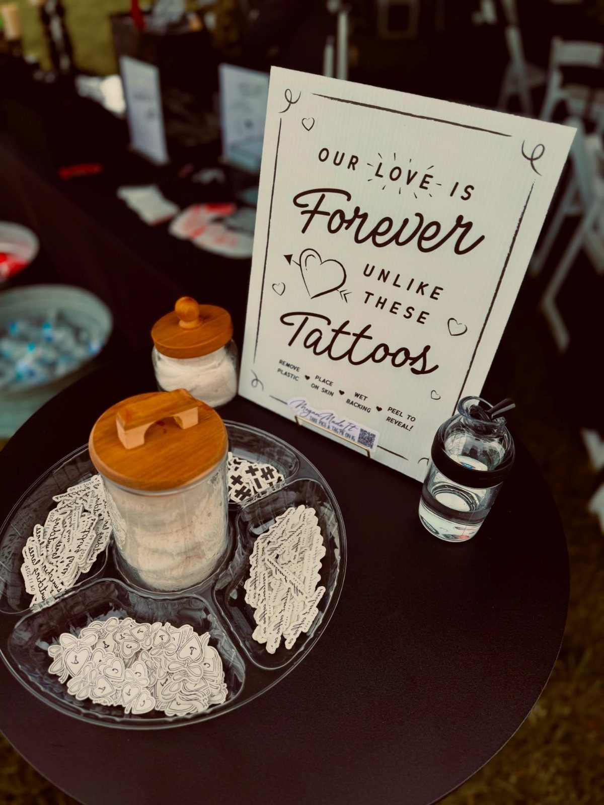 30 Wedding Guest Keepsakes Your Guests Will Actually Use 22 Temporary tattoo station with a sign and divided tray of tattoo sheets.