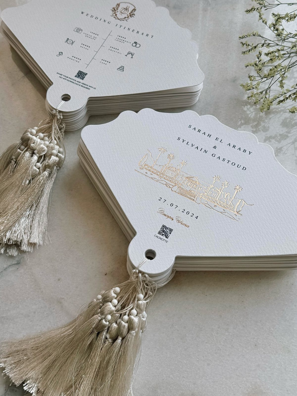 30 Wedding Guest Keepsakes Your Guests Will Actually Use 3 White scalloped wedding fans with gold foil lettering and elegant gold tassels.