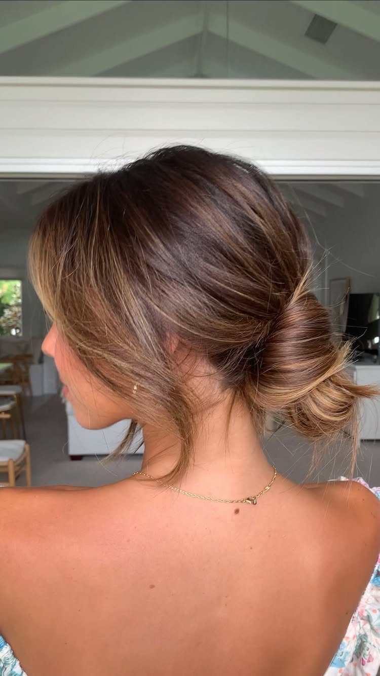Wedding Hair Styles for Straight Hair: 9 Ideas 4 Woman with a low loose bun and face-framing hair flicks from behind.
