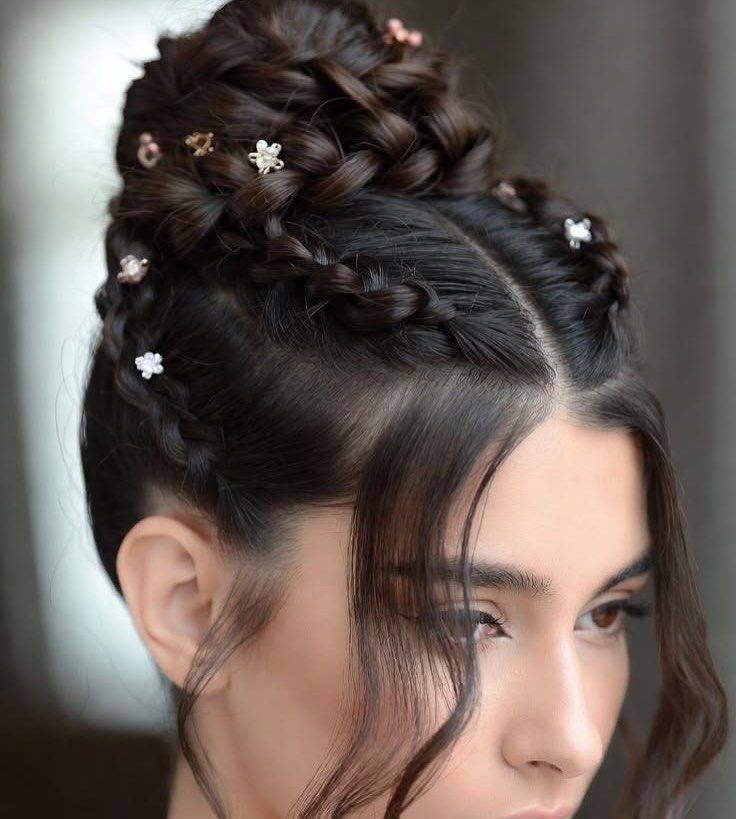 Intricate braided updo with floral accessories on a woman with dark brown hair.
