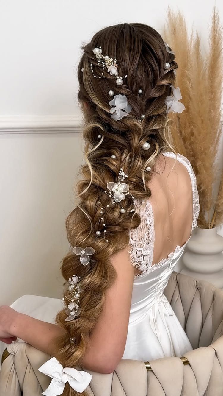 Woman with a long braided bridal hairstyle decorated with pearls and white flowers.