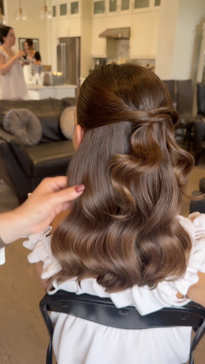 Woman with long brown wavy hair styled in a half up up-do