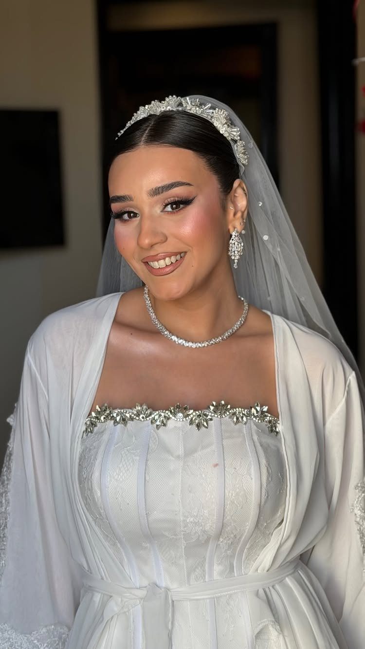 Bride with sleek middle-parted hair wearing a sparkling tiara and white veil.