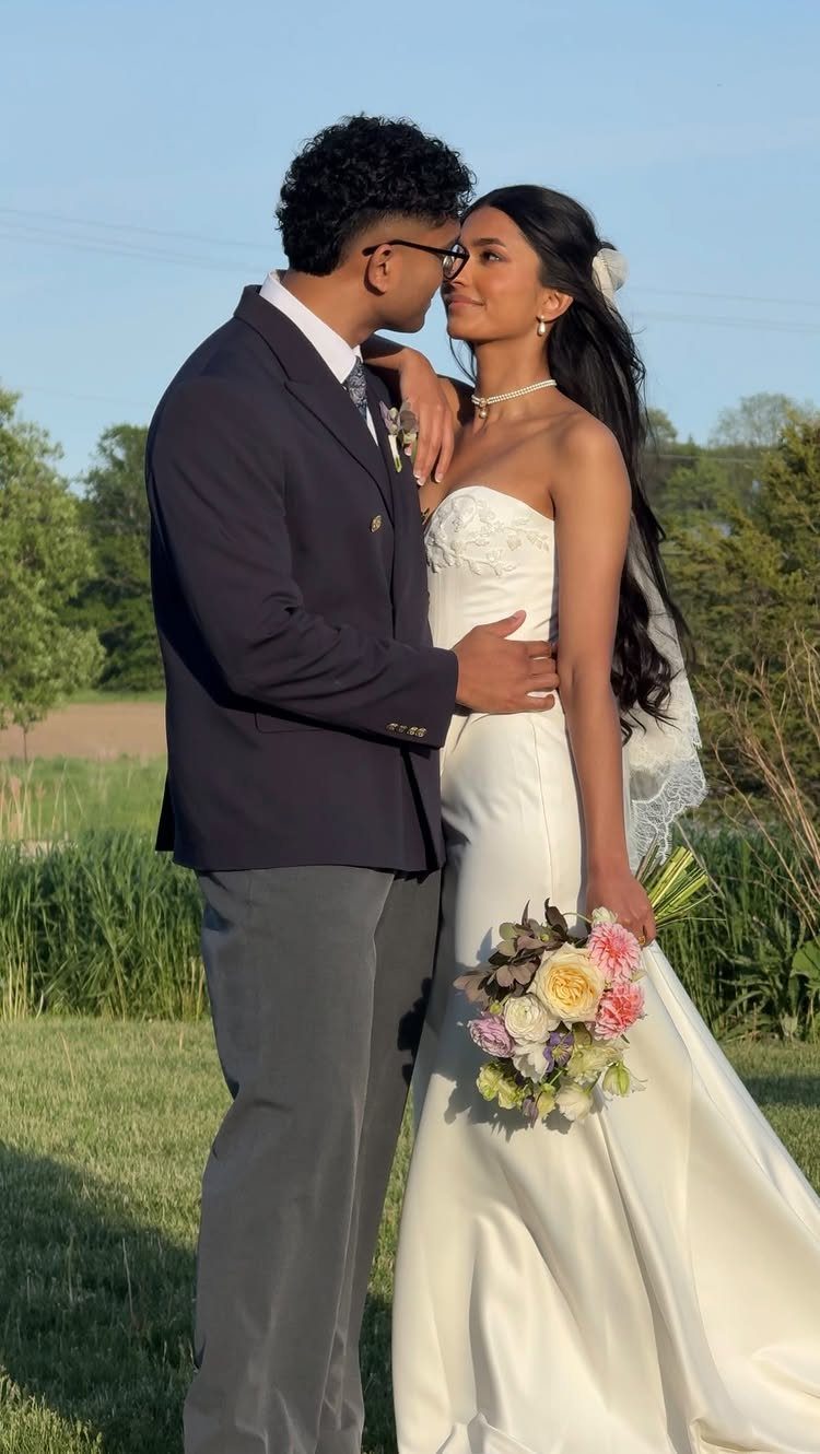 Bride with long dark hair down and a veil posing with her groom.