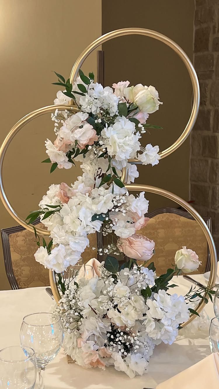 Interlocking gold rings decorated with white and pink roses as a wedding centerpiece
