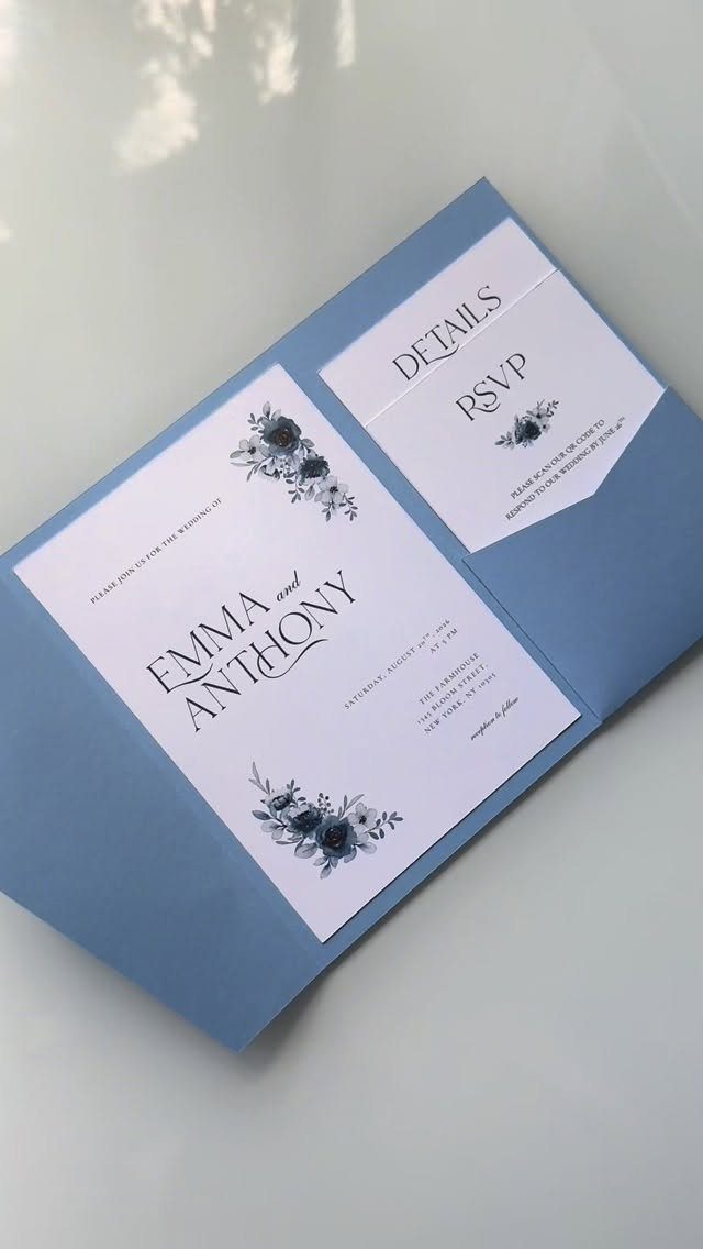 Wedding invitation with blue floral accents and matching blue envelope on white surface