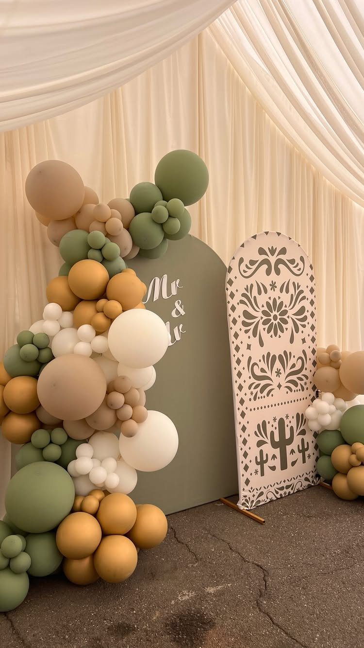 Balloon arch in sage and tan framing a wedding photo booth backdrop.