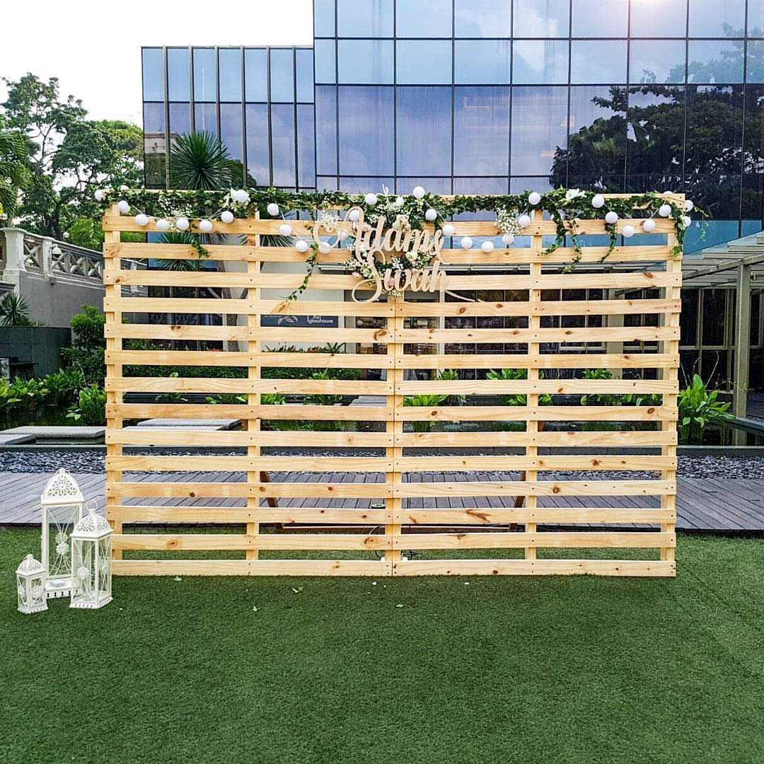Wooden pallet wall backdrop with white flowers and gold signage on green grass