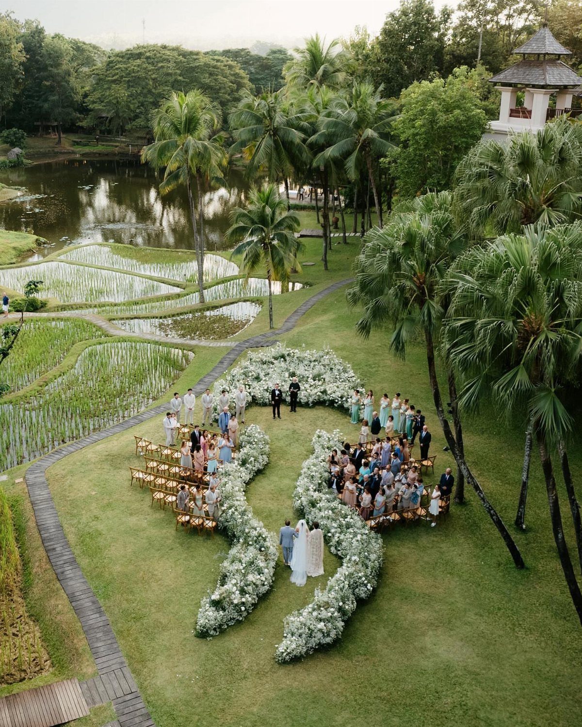 17 Wedding Ideas Pictures to Show Your Photographer 16 Aerial view of a wedding ceremony with a heart-shaped white floral aisle and guests.