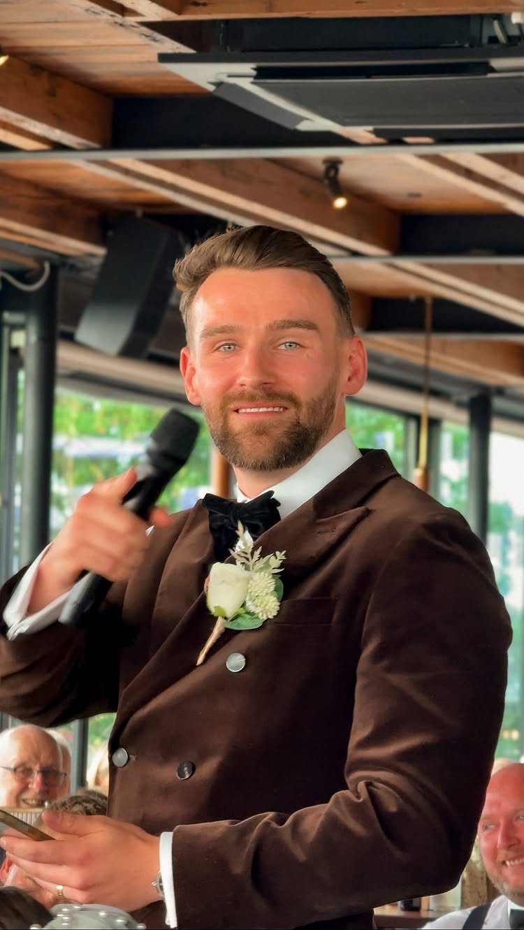 17 Wedding Ideas Pictures to Show Your Photographer 14 Groom in brown tuxedo holding a microphone and notes while giving a wedding speech.