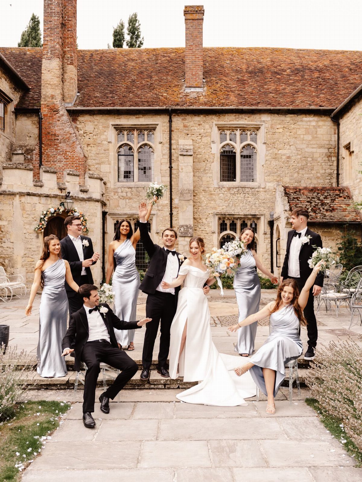 17 Wedding Ideas Pictures to Show Your Photographer 11 Wedding party posing playfully in front of a historic stone manor house.