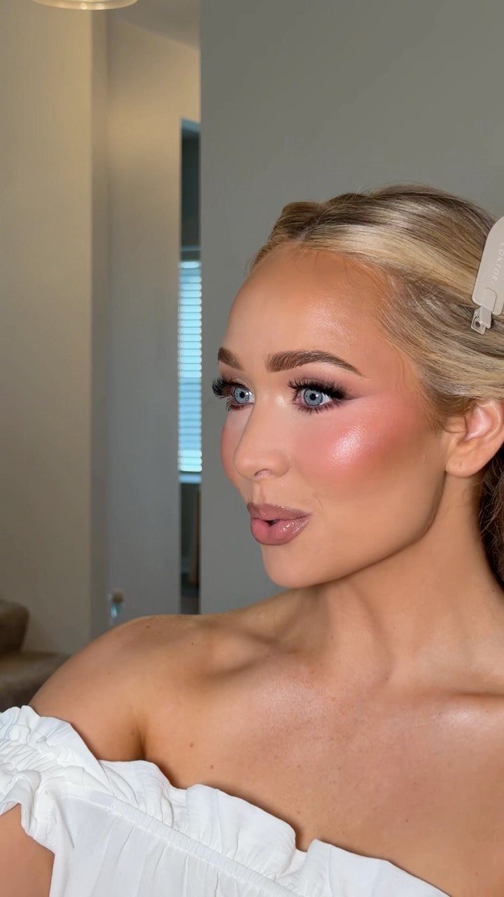 Woman with blonde hair wearing a white top and full bridal makeup look