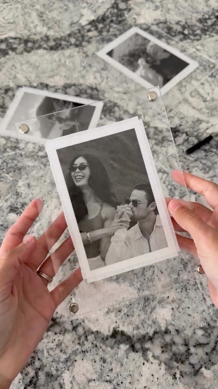 Polaroid photo of a couple in an acrylic frame on a marble surface.
