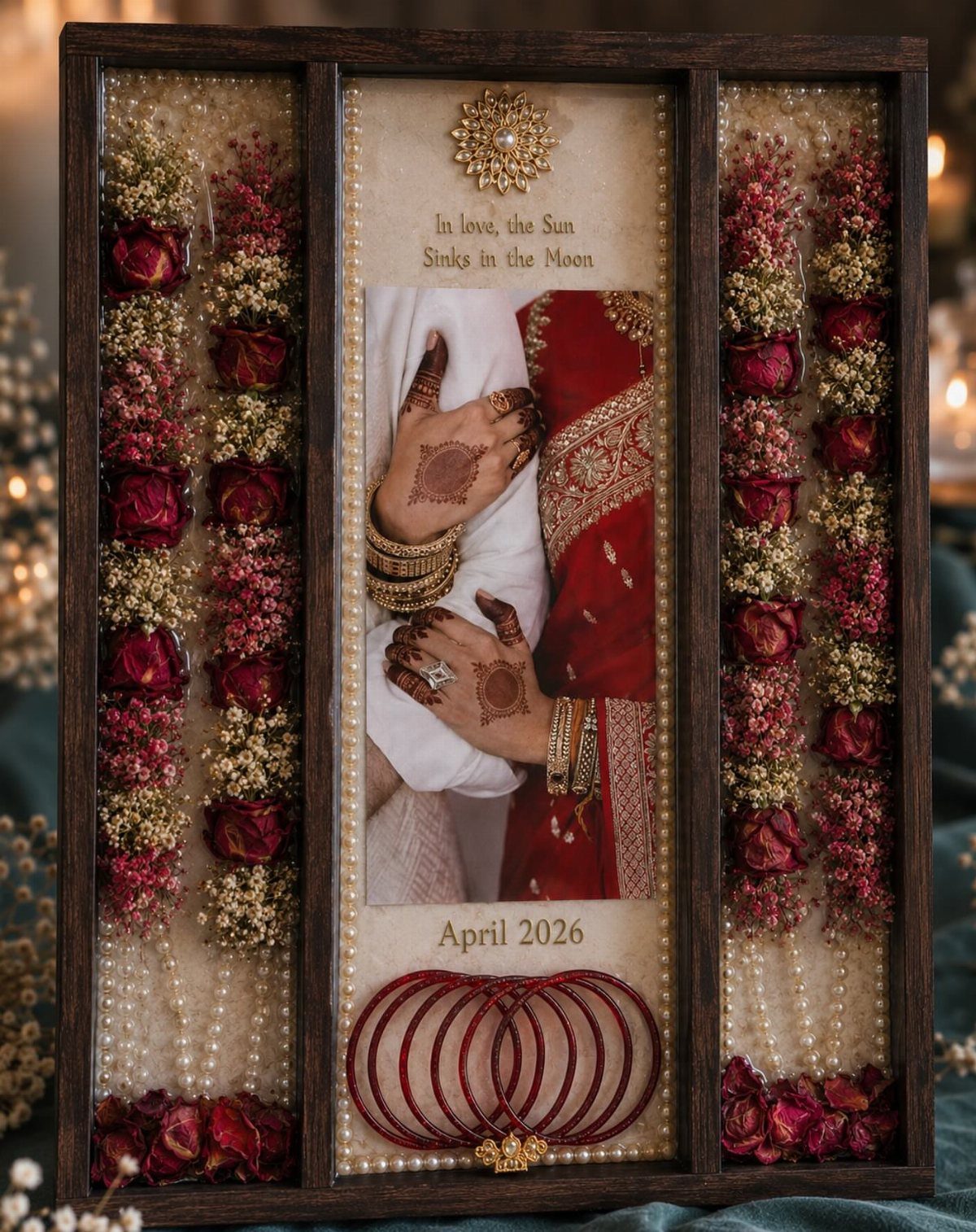 Wooden shadow box displaying wedding memories with photos, red bangles, and dried roses.