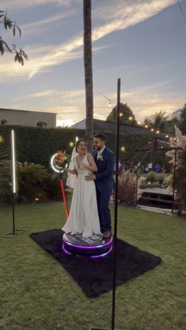Best Wedding Photo Station Ideas: 8 Booths and Backdrops 2 Bride and groom standing on a circular 360 degree photo booth platform outdoors.