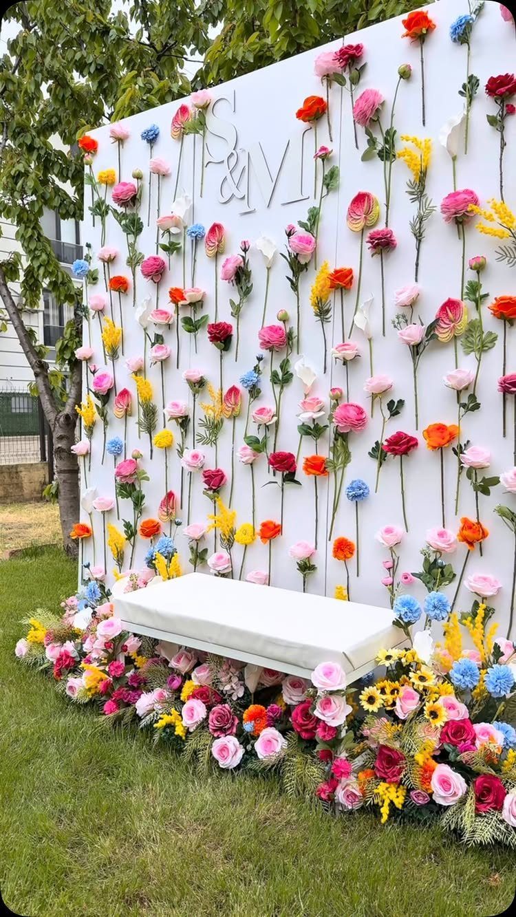 Best Wedding Photo Station Ideas: 8 Booths and Backdrops 6 Floral backdrop wall with silver initials and a white bench on green grass.