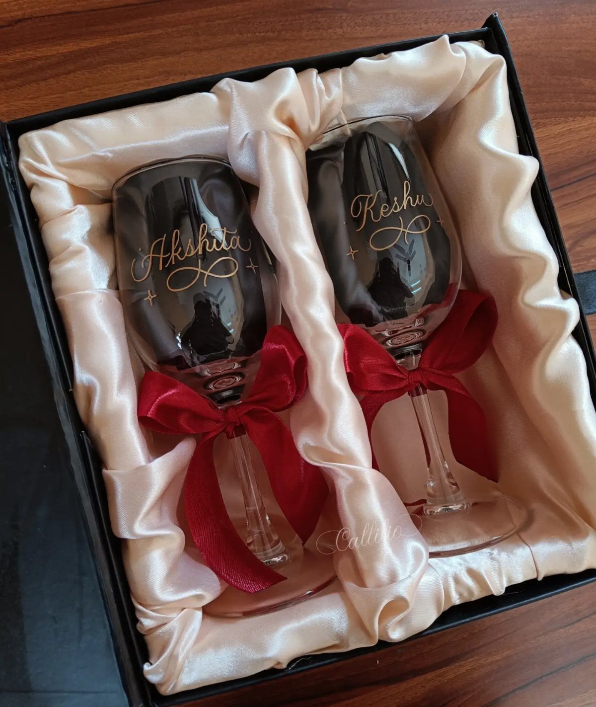 22 Wedding Present Ideas for Couples to Treasure 10 Black wine glasses with gold engraving and red ribbons in a satin-lined box.