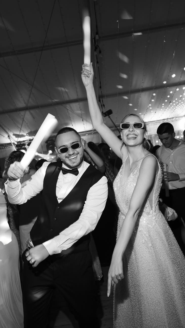 13 Wedding Reception Ideas for Guests Who Love Fun 7 Couple dancing at a wedding holding glowing LED foam sticks and wearing sunglasses.